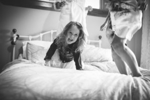 Flower girl jumping on the bed with Bride and Bridesmaids
